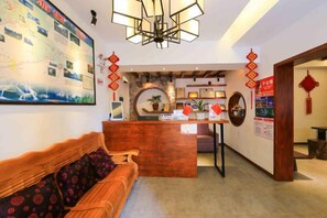 Una hall d'albergo con una reception, un divano e una parete con un grande quadro.