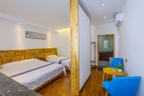 A hotel room with two beds, a wooden headboard, a small table with a chair, and a wall-mounted air conditioner. - Shanhai Coffee Inn (Zhangjiajie)