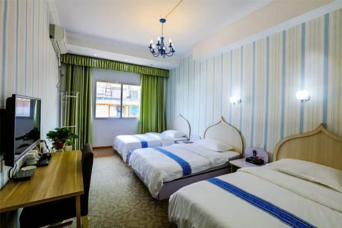 Une chambre d’hôtel avec deux lits, un bureau, une télévision et une fenêtre avec des rideaux.