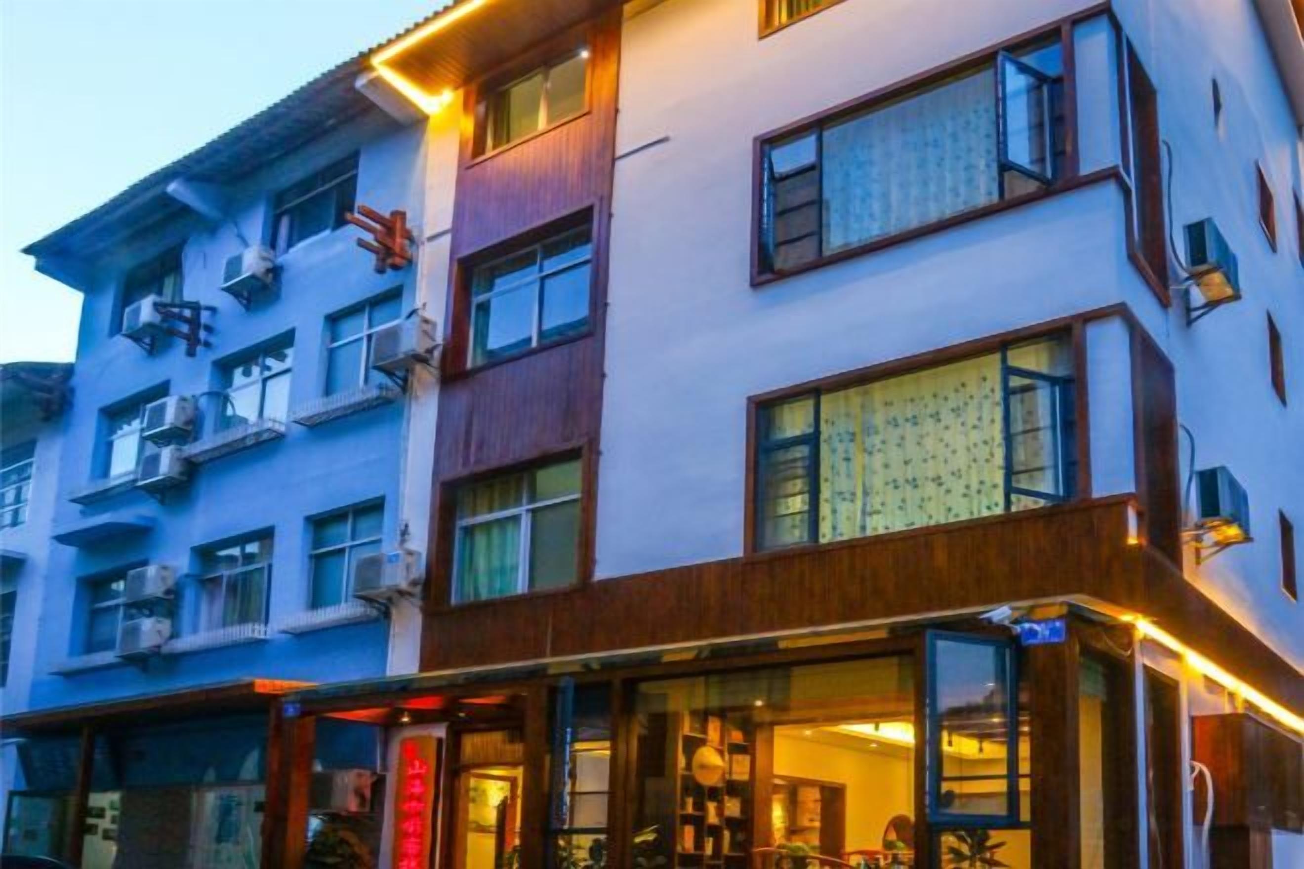 A multi-story hotel with balconies, large windows, and a ground-level entrance with a sign.