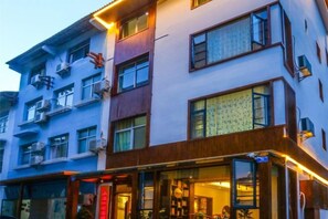 A multi-story hotel with balconies, large windows, and a ground-level entrance with a sign. - Shanhai Coffee Inn (Zhangjiajie)