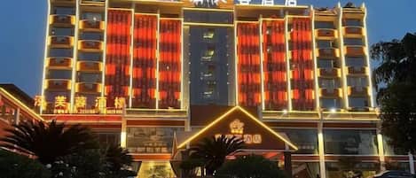 Um hotel com vários andares, entrada imponente e fachada bem iluminada.