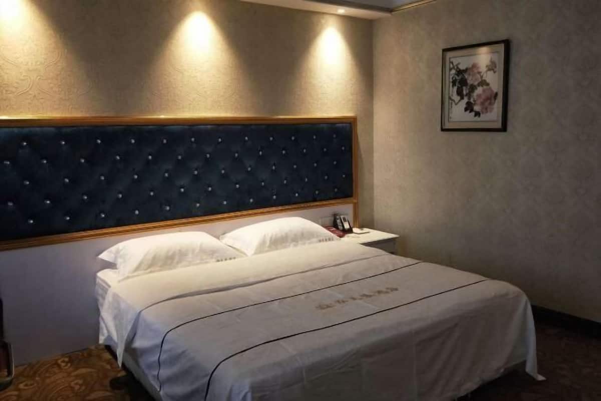 Ein Hotelzimmer mit Bett, Nachttisch und einem Bild im Bilderrahmen an der Wand.
