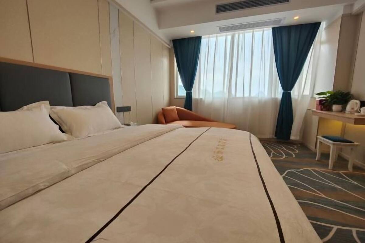 Ein Hotelzimmer mit Bett, Schreibtisch, Stuhl und einem Fenster mit Vorhängen.