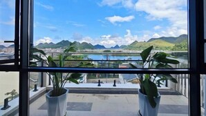 Un balcón con plantas en macetas, vistas despejadas de la ciudad y montañas al fondo.