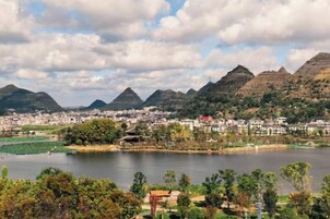 A panoramic view of a city with a lake, mountains, and traditional architecture.