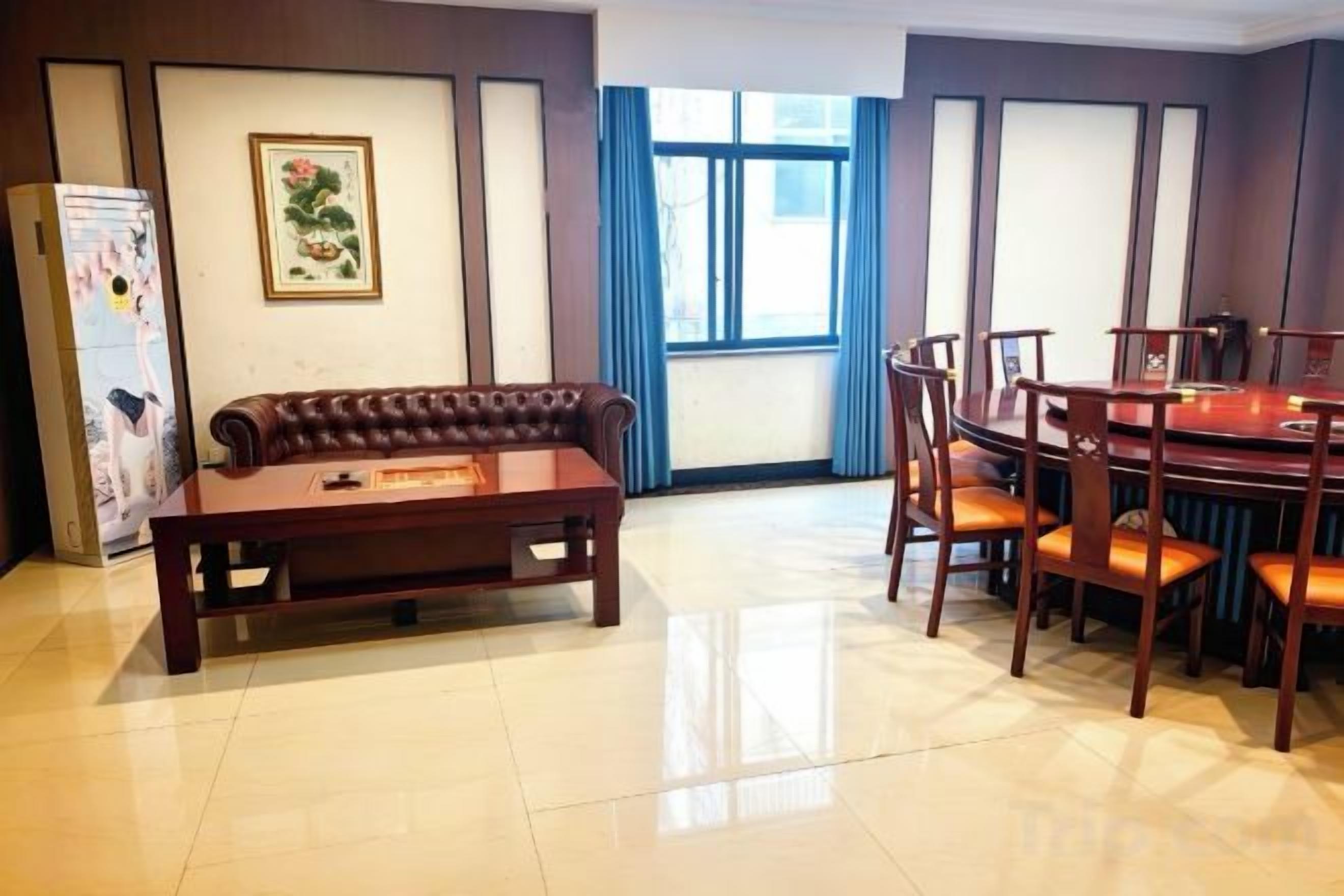 A room with a sofa, a dining table with chairs, a refrigerator, and a window with curtains.