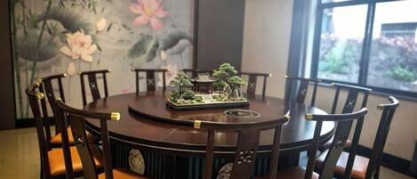 A round dining table with chairs, a decorative centerpiece, and a large painting on the wall.