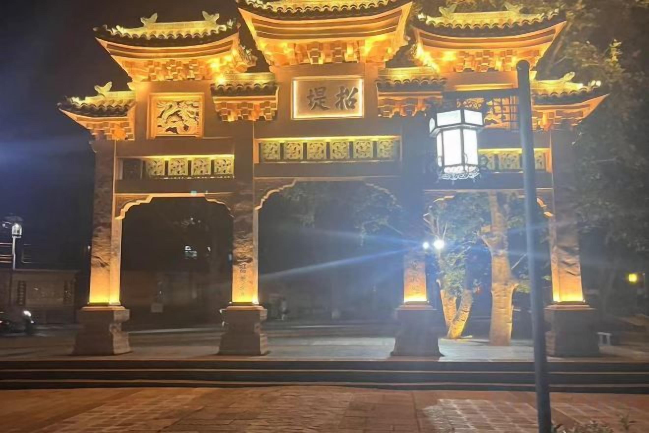 Une porte chinoise traditionnelle, ornée de motifs complexes et illuminée par un éclairage chaleureux.