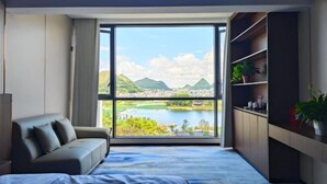 Un dormitorio moderno con un ventanal grande, una cama, un sofá y una estantería empotrada.