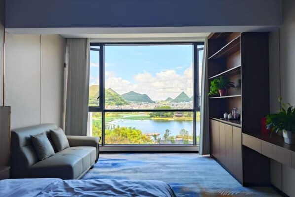 A modern bedroom with a large window, a bed, a sofa, and a built-in bookshelf. - Hongfurong Hotel (Anlong)