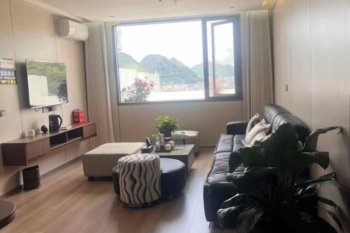 Ein modernes Wohnzimmer mit einer Couch, einem Hocker, einem Couchtisch und einem an der Wand montierten Fernseher.