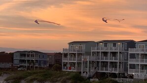 Ein Hotel direkt am Strand mit mehrstöckigen Gebäuden, Balkonen und einem sandigen Vordergrund.