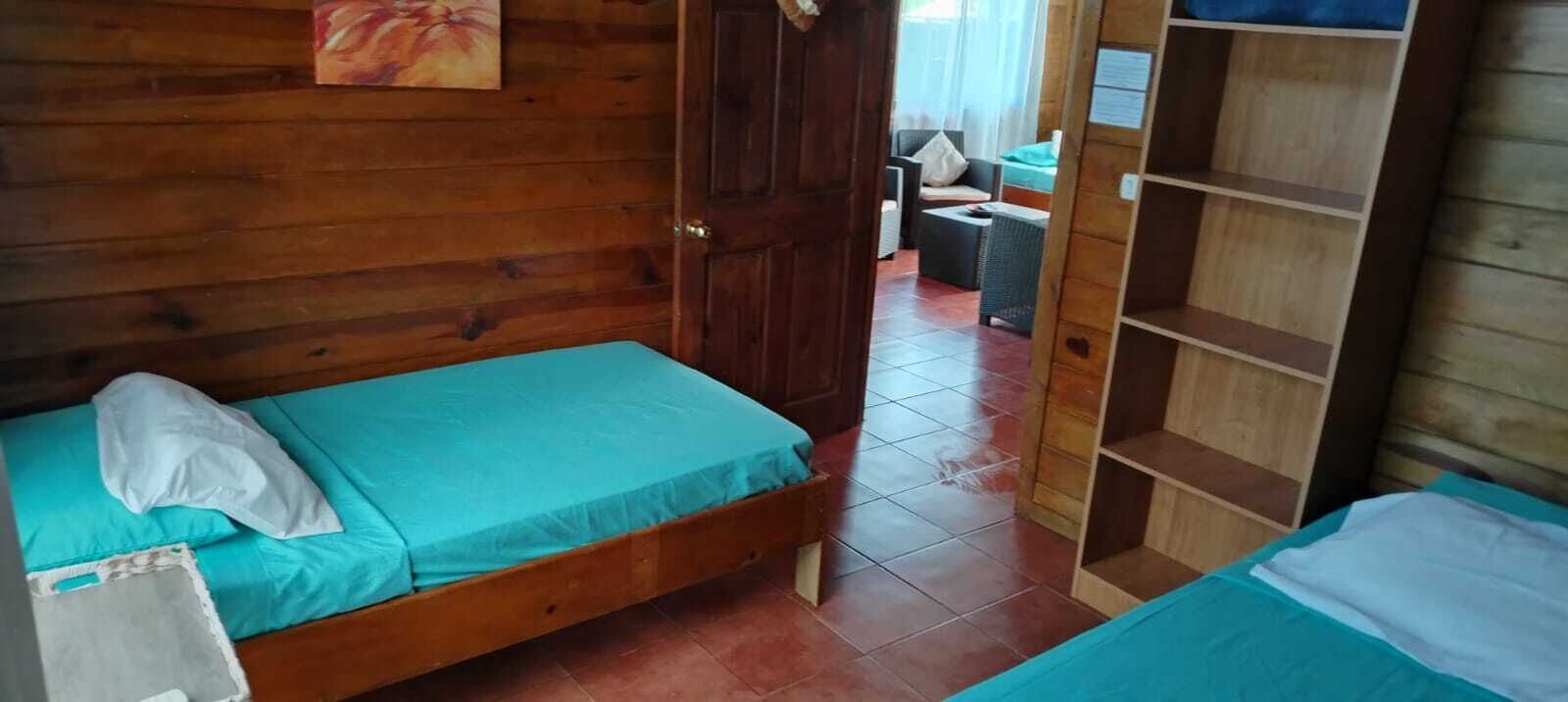 Una habitación de madera con una cama, un armario y un pequeño rincón de descanso con una mesa y sillas.