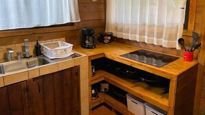 Una cocina compacta con gabinetes de madera, un lavamanos, una estufa y una cafetera.