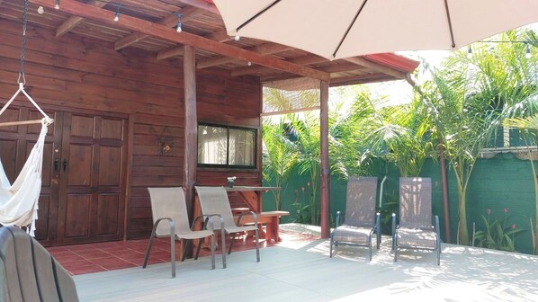 A wooden cabin with a covered patio, outdoor seating, and a hammock.