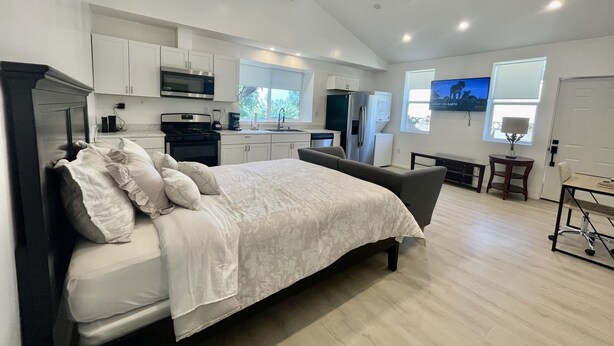 A modern bedroom with a large bed, a desk, and a kitchenette in the background. - ENTIRE MODERN LUXURY STUDIO PRIVATE FOR UP TWO PEOPLE AT WEST HIILS  (Los Angeles)