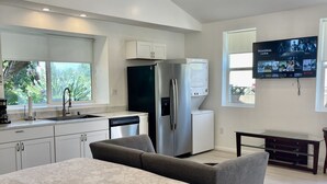 A modern bedroom with a large bed, a built-in bench, a TV mounted on the wall, and a kitchen area with a refrigerator and cabinets. - ENTIRE MODERN LUXURY STUDIO PRIVATE FOR UP TWO PEOPLE AT WEST HIILS  (Los Angeles)