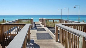 Une promenade en bois menant à la plage, d’où l’on a une vue dégagée sur l’océan.