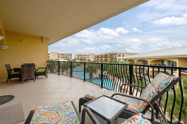 A balcony with wicker furniture, a pool, and a view of other buildings. - Top Floor Corner | Two Pools | Private Beach (Santa Rosa Beach)