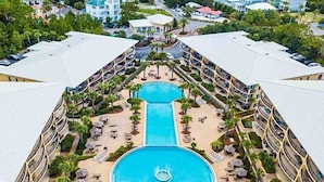 Un hôtel doté d’une piscine centrale, entourée de transats et de palmiers, et offrant de nombreux balcons avec vue sur les environs.