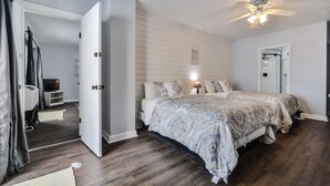 Un dormitorio con una cama grande, un ventilador de techo y una puerta que da a otra habitación.