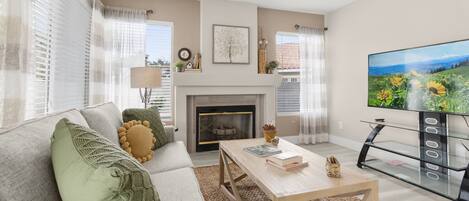 A living room with a fireplace, a sofa, a coffee table, and a TV.