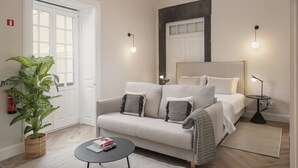 A modern hotel room with a sofa, bedside tables, a potted plant, and a large mirror. - Luxury, art and elegance - FAA Belas Artes 2 (Funchal)