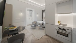 Ett modernt kök med inbyggda vitvaror, en matplats med ett runt bord och stolar samt ett vardagsrum med en soffa och ett soffbord.