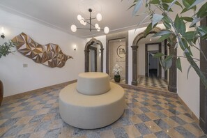 Un intérieur moderne avec un sol à carreaux, un espace salon central et une œuvre d’art géométrique murale.