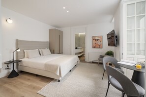 Une chambre moderne avec un lit, une table de chevet, une lampe et un bureau avec une chaise.