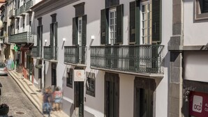 Una hilera de edificios blancos con contraventanas verdes y balcones.