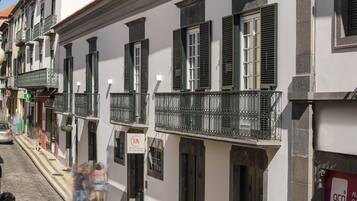 A row of white buildings with green shutters and balconies.