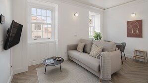 Una sala de estar con un sofá, una mesa de centro y un televisor montado en la pared.