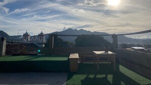 Une terrasse sur le toit offrant une vue sur les montagnes et une église.