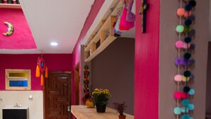 Une cuisine avec une table en bois et des tabourets de bar, un mur rose et une guirlande décorative de pompons.