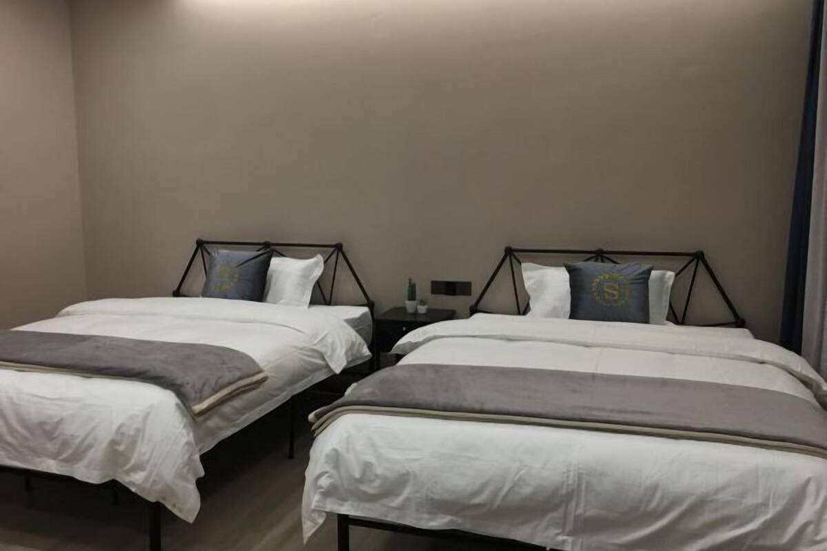 A twin bedroom with two single beds, each with a headboard, a bedside table, and a lamp.
