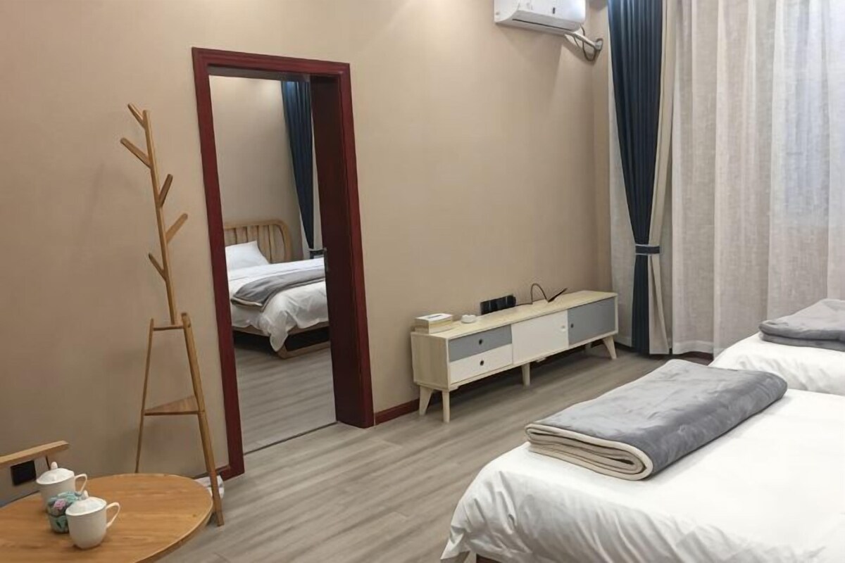 A hotel room with a bed, a bedside table, a mirror, a wardrobe, and a small table with a teapot.