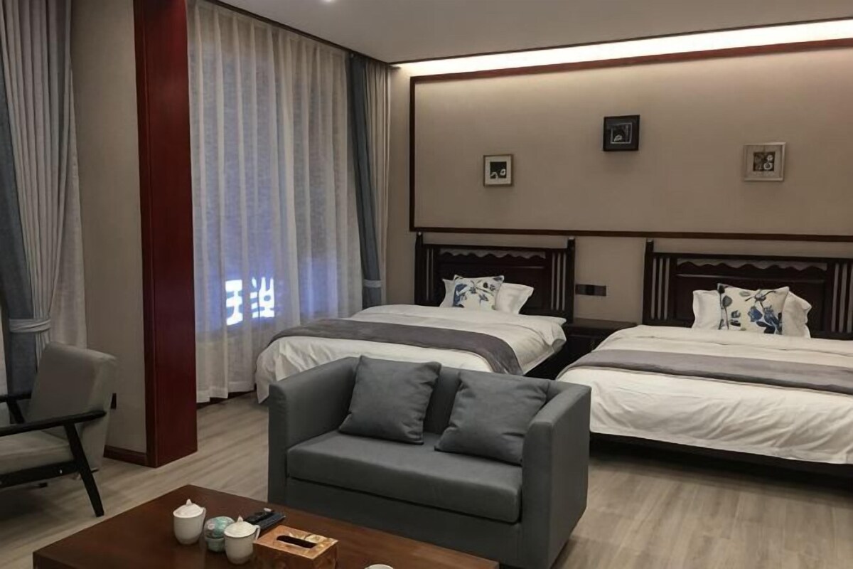 A hotel room with two beds, a sofa, a coffee table, and a chair.