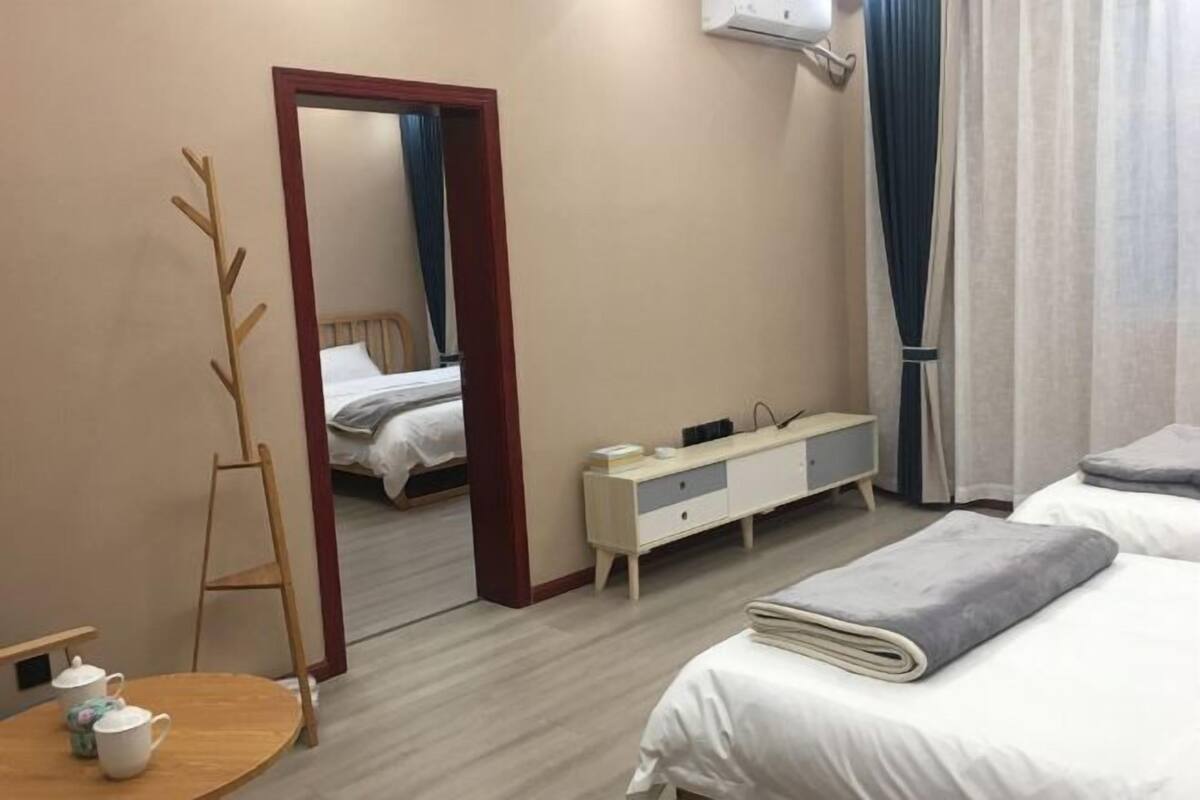 A hotel room with a bed, bedside table, mirror, wardrobe, and a wooden ladder.