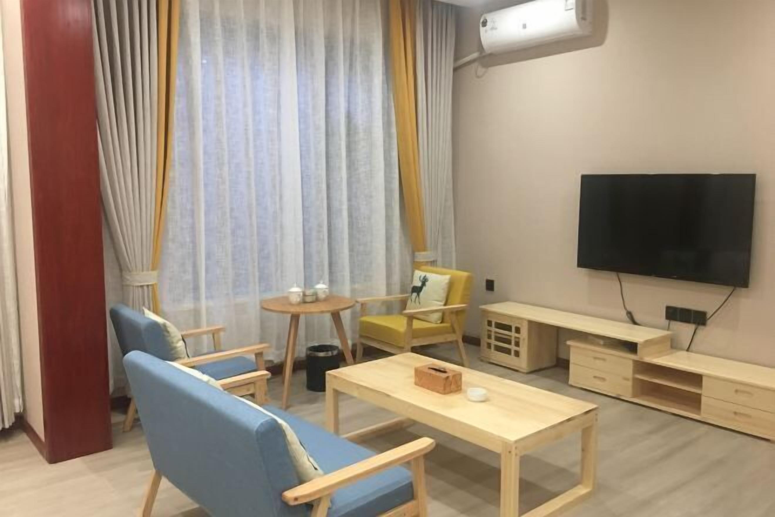 A modern living room with a sofa, chairs, a coffee table, a TV, and a small table with items on it.