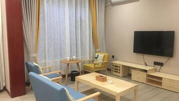 A modern living room with a sofa, chairs, a coffee table, a TV, and a small table with items on it.