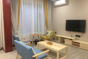 A modern living room with a sofa, chairs, a coffee table, a TV, and a small table with items on it. - Puxin Inn (Dali City)
