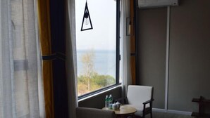 A room with a view of the sea, a table with a chair, and a hanging light fixture. - Puxin Inn (Dali City)