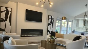 Ein modernes Wohnzimmer mit Kamin, weißen Sofas und abstrakter Kunst an den Wänden.