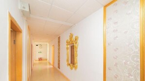 En hotellkorridor med ett kaklat golv, en trädörr till vänster och en dekorativ spegel till höger.