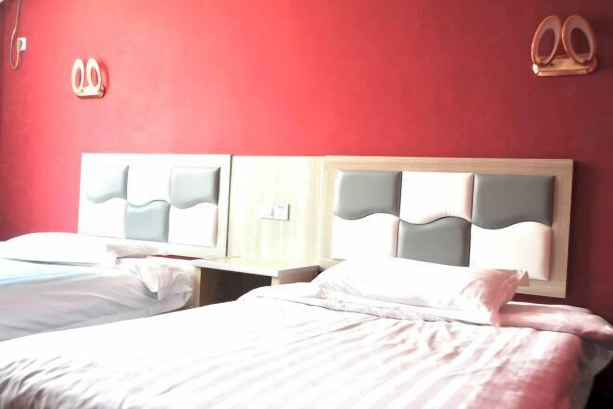 A hotel room with two beds, each with a headboard and bedside tables.