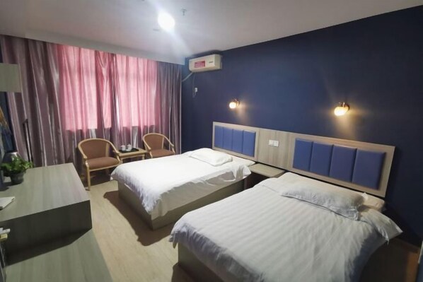Habitación de hotel con dos camas, un escritorio, una silla y una ventana con cortinas.
