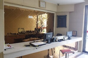A reception desk with a computer, a telephone, and a framed certificate. There is a window with a view of the outside. - Fuerte Chain Hotel Guangde Xinjinjiang (Guangde)