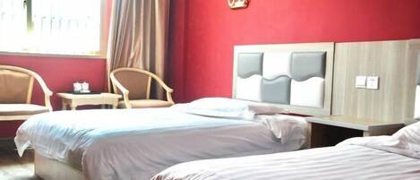 A hotel room with two beds, a wooden headboard, a small table, and a chair.